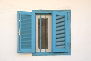 Window with blue shutters and frames of a white house of Asilah (Morocco).