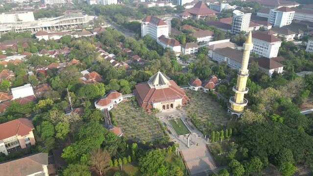Aerial view of Masjid Kampus Universitas Gadjah Mada or UGM Mosque where Muslims worship with dome and tower surrounded by trees. Eid al-Fitr and Eid al-Adha. Bright Sunlight - During the day.
