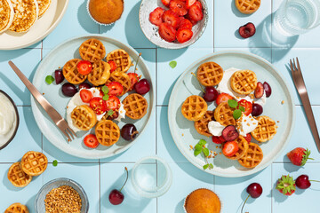 Delicious summer breakfast. Sweet breakfast with mini waffles and fresh berries, strawberries and cherries. Top view.