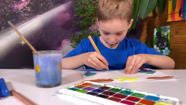 Youthful artistic imagination, childhood hobby. A cute little boy expresses his creativity by joyfully drawing with colored pencils surrounded by artistic supplies, whimsical pictures, indoor plants