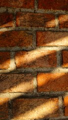 The brick wall in the evening has shadows from the slats.