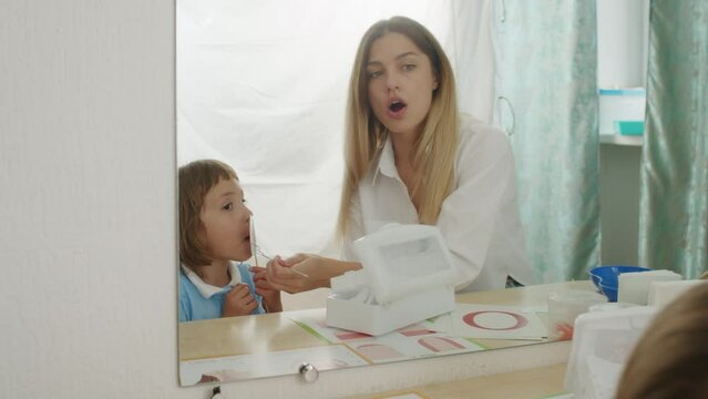 In a cozy office, speech games unite child, woman therapist. Laughter, learning, articulation joyful education.