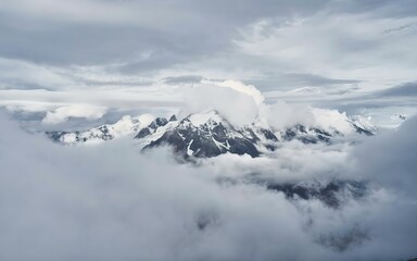 Fototapeta na wymiar Wonderful minimalist landscape with big snowy mountain peaks above low clouds.