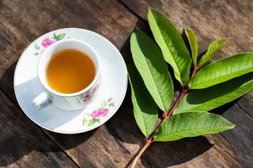 Guava leaf tea in a white cup on a wooden table, herbal drink for diarrhea and...