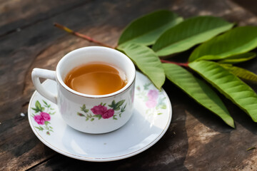 Guava leaf tea in a white cup on a wooden table, herbal drink for diarrhea and cholesterol.selective focus.