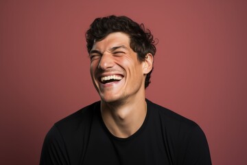 Portrait of a young man laughing against a red background. Human emotions and facial expressions concept.