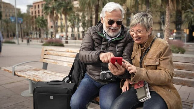Senior traveler couple sharing media on online cell phone app in the city 