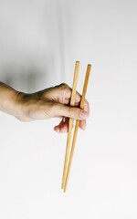 Woman's hand holding two chinese chopsticks on a white background
