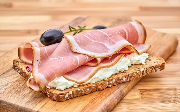 Whole Grain Crispbread with Ham, Cream Cheese and Olives on Bamboo Cutting Board. Easy Breakfast