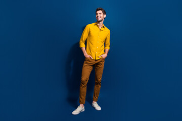 Full body photo of handsome young guy hands pockets look empty space wear trendy yellow outfit isolated on dark blue color background