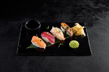 Classic nigiri sushi with salmon, tuna, eel, and shrimp on a black slate