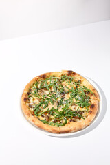 Italian pizza with cheese and mushrooms, topped with fresh arugula