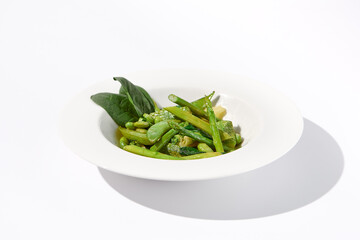 Fresh green vegetable garnish featuring asparagus, zucchini, and edamame beans on isolated white background