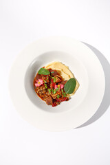 Braised beef with vegetables and mushrooms, topped with mashed potatoes on a white background, top view - perfect for comfort food menus