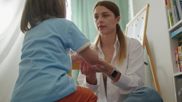 Engaged in therapy: kid and female pathologist in white, mixing education, fun. Office alive with language, laughter.