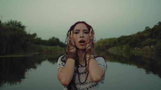 With an air of mystery, a woman enacts a spiritual rite by the river, her costume and artistry paying homage to the deep-rooted traditions and mystical energy of paganism.