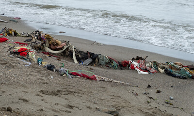 Close up of piles of discarded clothes and textiles washed ashore onto beach from ocean on a tropical island destination