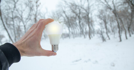 Male hand showing light bulb at winter.