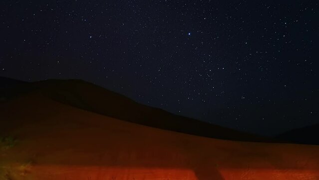 Star-trail timelapse of blue night sky with milky way, stars field and galaxies, from dunes of Empty quarter desert or Rub' al-Khali desert on Jannuary in Oman.