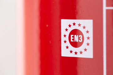 closeup of a marking on a fire extinguisher that complies with european norm regulation as a safety device to prevent blaze and fire hazards