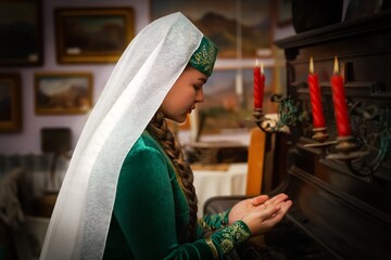 Muslim woman in old retro tradition dress praying on home