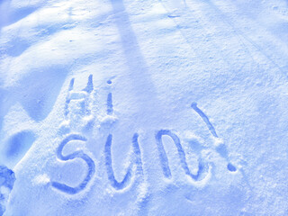 Inscription Hi Sun, written on white background of the snow. Top view. Flat lay. Winter, spring. Waiting for summer and spring
