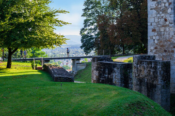 person enjoys the view from the bridge over the fortification moat of a medieval stone fortress...