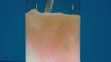 The video showcases a tall, clear glass being filled with peach-colored soda water, invoking the freshness of spring and the energy of the year's chosen hue. Transparent ice cubes float buoyantly as