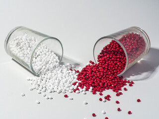 hot cut type red and white masterbatch granules spilled from a shot glass on a white background,...
