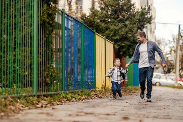 A farther and son rushing to kindergarten and holding hands.