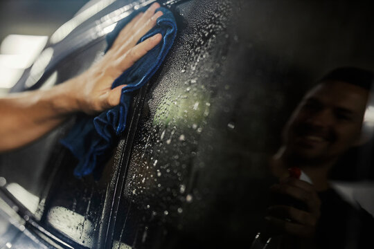 Hand cleaning car window with a reflection on it.