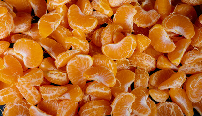 Peeled tangerines on a black background. Slices of tangerine or mandarin fruit close up