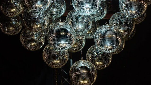 Silver mirror balls shimmer and sparkle in darkness as light reflects