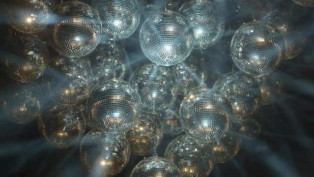 Bright spinning mirror balls sparkle light beams in black background