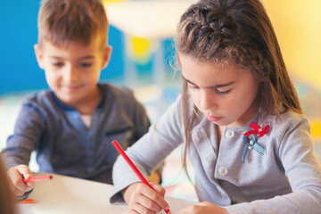 Girl and boy drawing in the schoolroom
