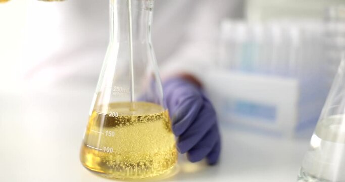 Scientist expert pours perfume oil and petroleum products into glass bottle closeup. Analysis of oil and oil products