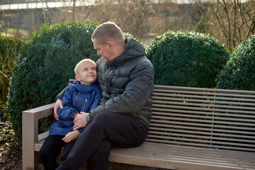 Autumnal Family Affection: Father, 40 Years Old, and Son - Beautiful 8-Year-Old Boy, Seated in the...