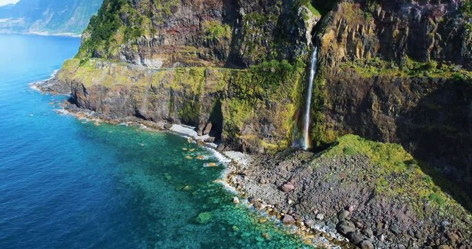 Waterfall Miradouro do V&eacute;u da Noiva Madeira waterfall near the coast in Madeira, Portugal. 
Aerial 4K footage of a drone flight over waterfall cascades over the rockface onto the regional road. 
Coast