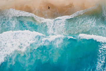 Surfer walk on beach with blue ocean and waves. Aerial view