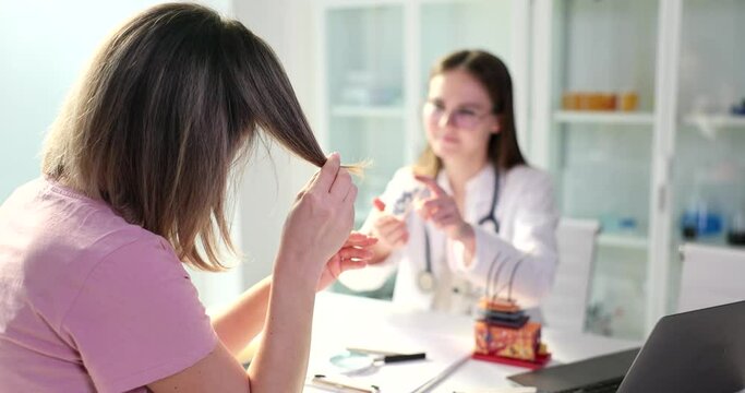 Doctor offers cure for split ends to female patient in clinic. Pharmacological products for hair restoration