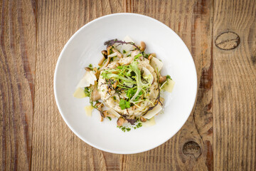 Top view of mushroom risotto with truffle in a white bowl on a wooden background
