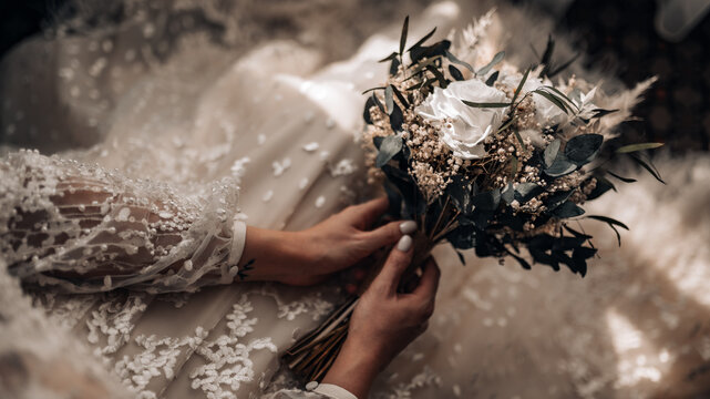 wedding bouquet in boho style collected from wild flowers, the bride holds a bouquet in her hand, in nature, white dress, live plants, a composition of dried flowers