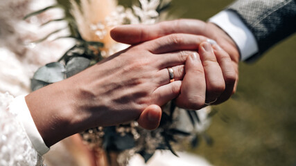 Young married couple holding hands, ceremony wedding day. Groom holding bride's hand, close up