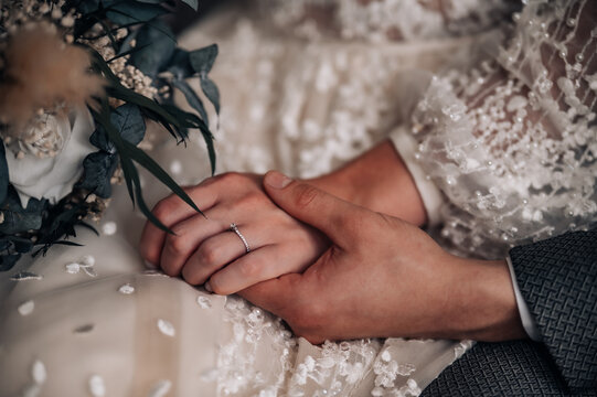 Young married couple holding hands, ceremony wedding day. Groom holding bride's hand, close up