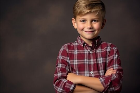 Portrait of a smiling little boy in a plaid shirt on a dark background