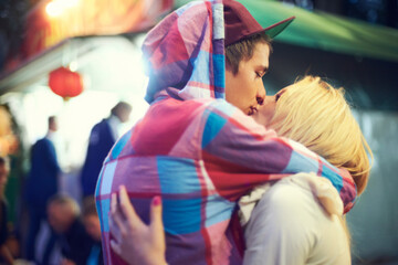 Couple, hug and kiss with love at music festival for bonding, affection or celebration together....