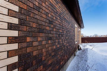A building with brickwork walls, wooden fixtures, and covered in snow under a cloudy sky.