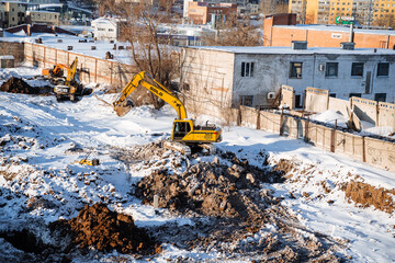 A Yellow Excavator Is Digging A Hole In The Snow