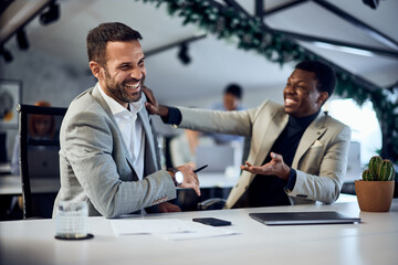 Two male colleagues laughing while working together in the co-working space.