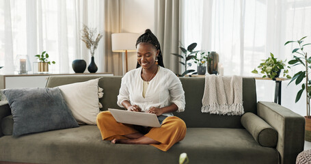 Black woman on sofa, smile and typing on laptop for remote work, social media or blog post research...